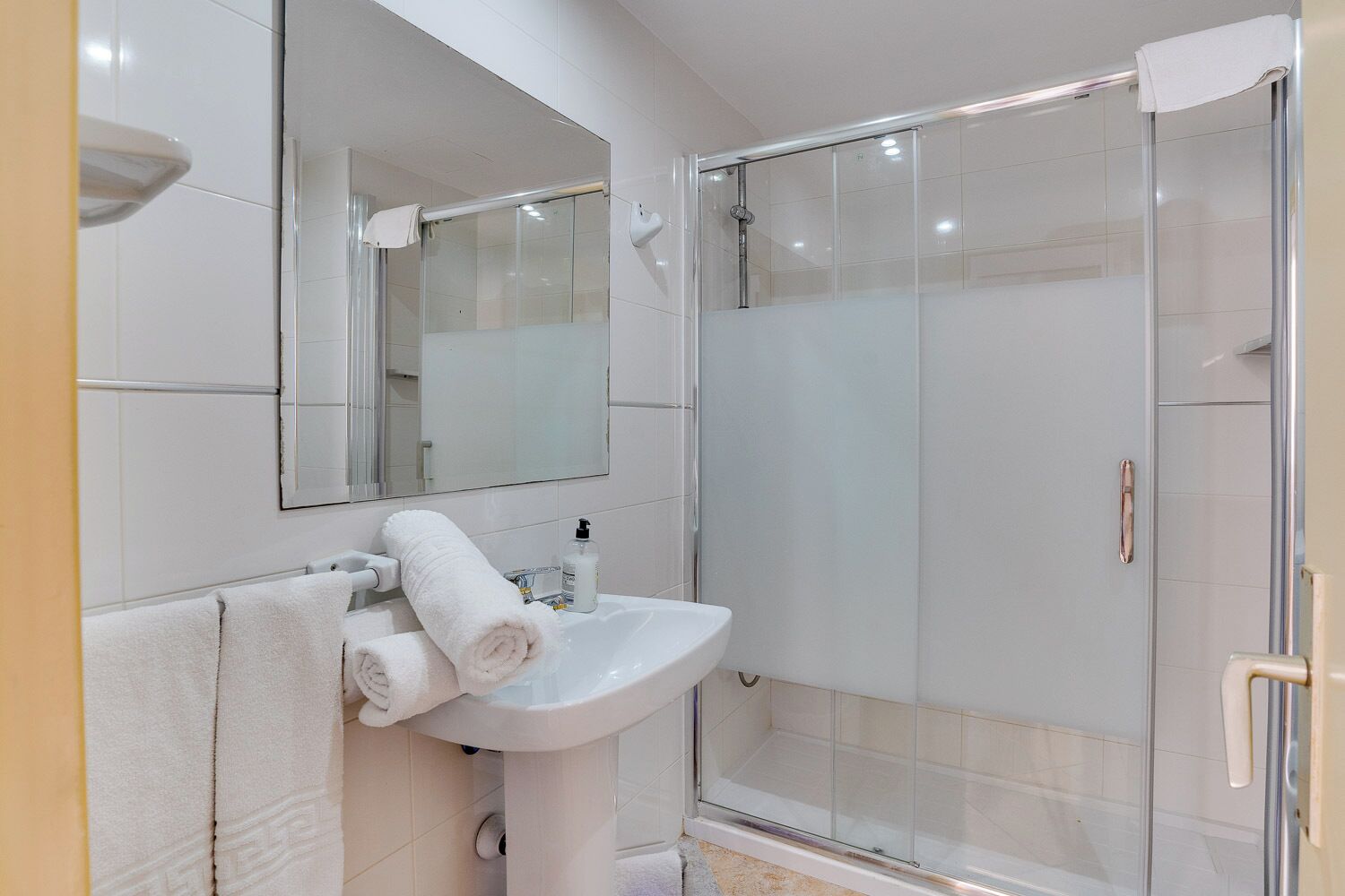 A modern bathroom with a glass-enclosed shower, a white sink, and a mirror above the sink.