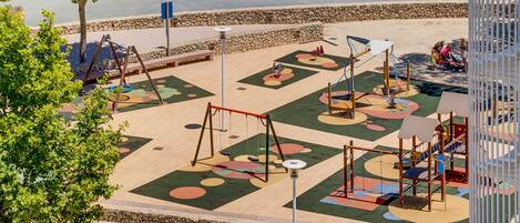 A playground with various play structures and a paved area with colorful patterns.
