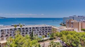 Un hotel de varios pisos con balcones que dan a una playa y al mar.
