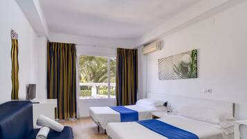 Una habitación de hotel con dos camas, un escritorio, una silla, un televisor y un ventanal con cortinas.