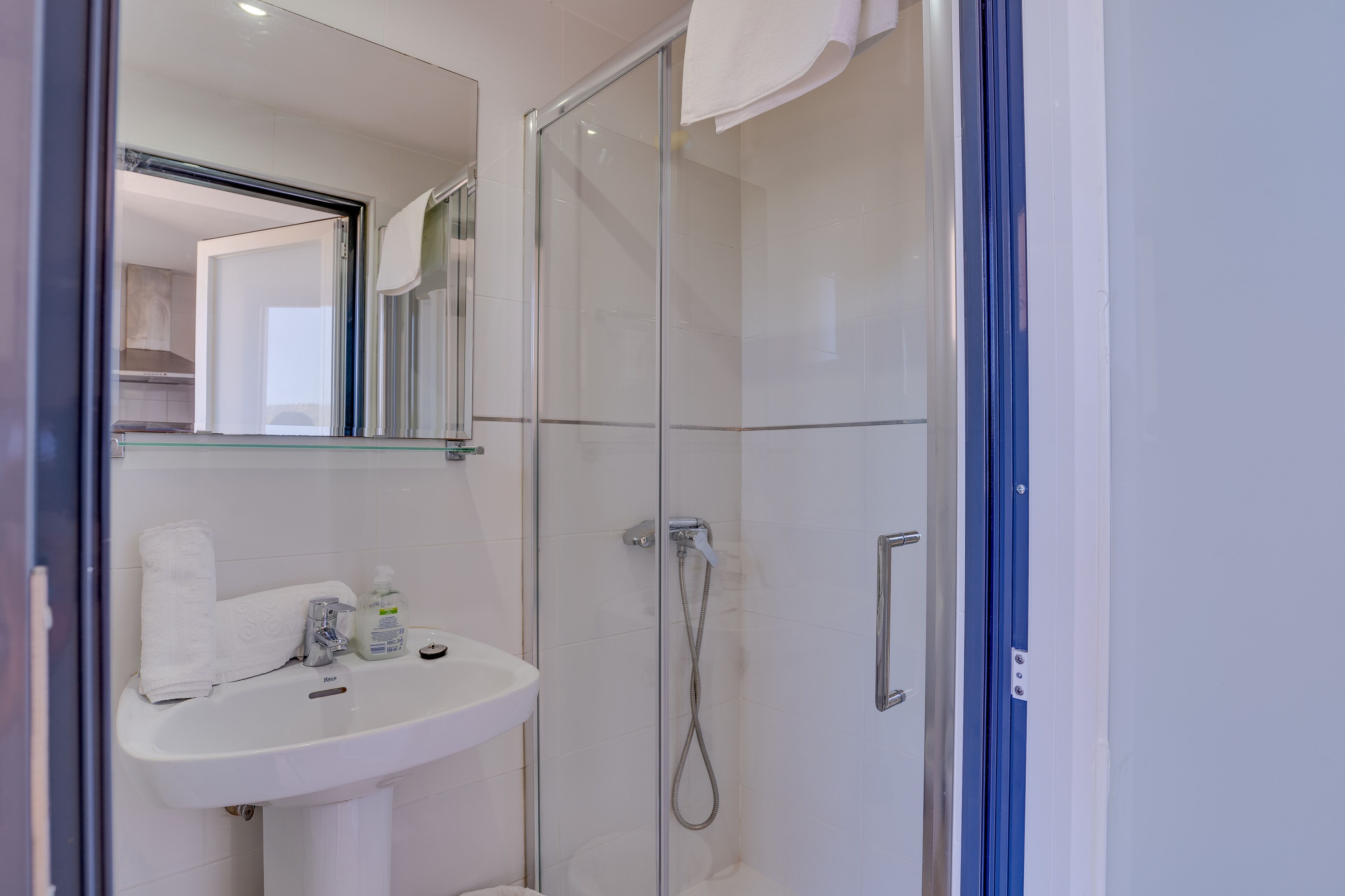 A modern bathroom with a glass-enclosed shower, a white sink, and a mirror above the sink.
