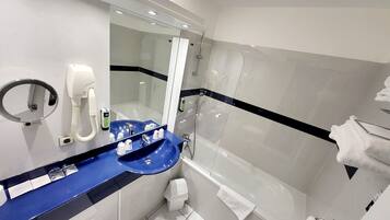 A modern bathroom with a blue sink, a handheld mirror, a handheld hair dryer, and a glass shower enclosure.