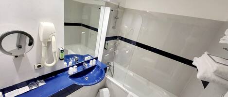 Un baño moderno con un lavamanos azul, un espejo de mano, un secador de pelo portátil y una cabina de ducha de vidrio.
