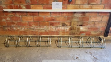 Pared de tijolos com uma placa indicando "VELOS CUSTOMER BIKE" e um suporte de bicicletas com vários ganchos.