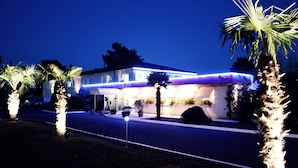 A hotel with a well-lit facade, palm trees, and a clear night sky.