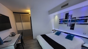 A modern hotel room with a bed, desk, and a large mirror.