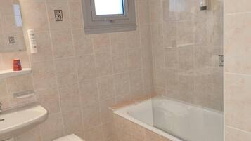 Un baño con bañera, lavamanos y un taburete pequeño.
