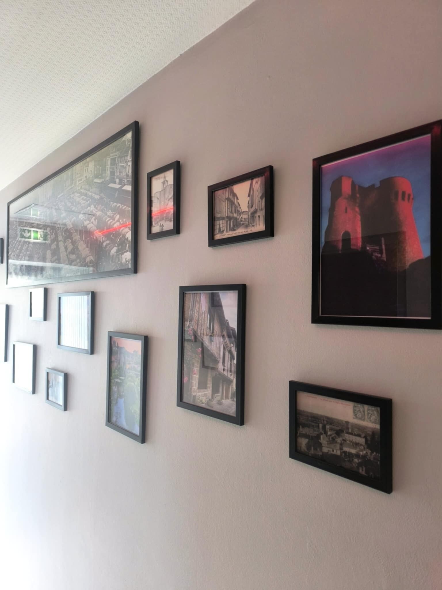 A wall with multiple framed pictures of buildings and a castle, likely in a hotel or similar accommodation.