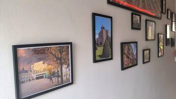 A hallway with framed pictures on the wall, including various buildings and landscapes.