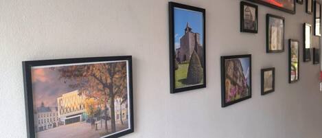 A hallway with framed pictures on the wall, including various buildings and landscapes.