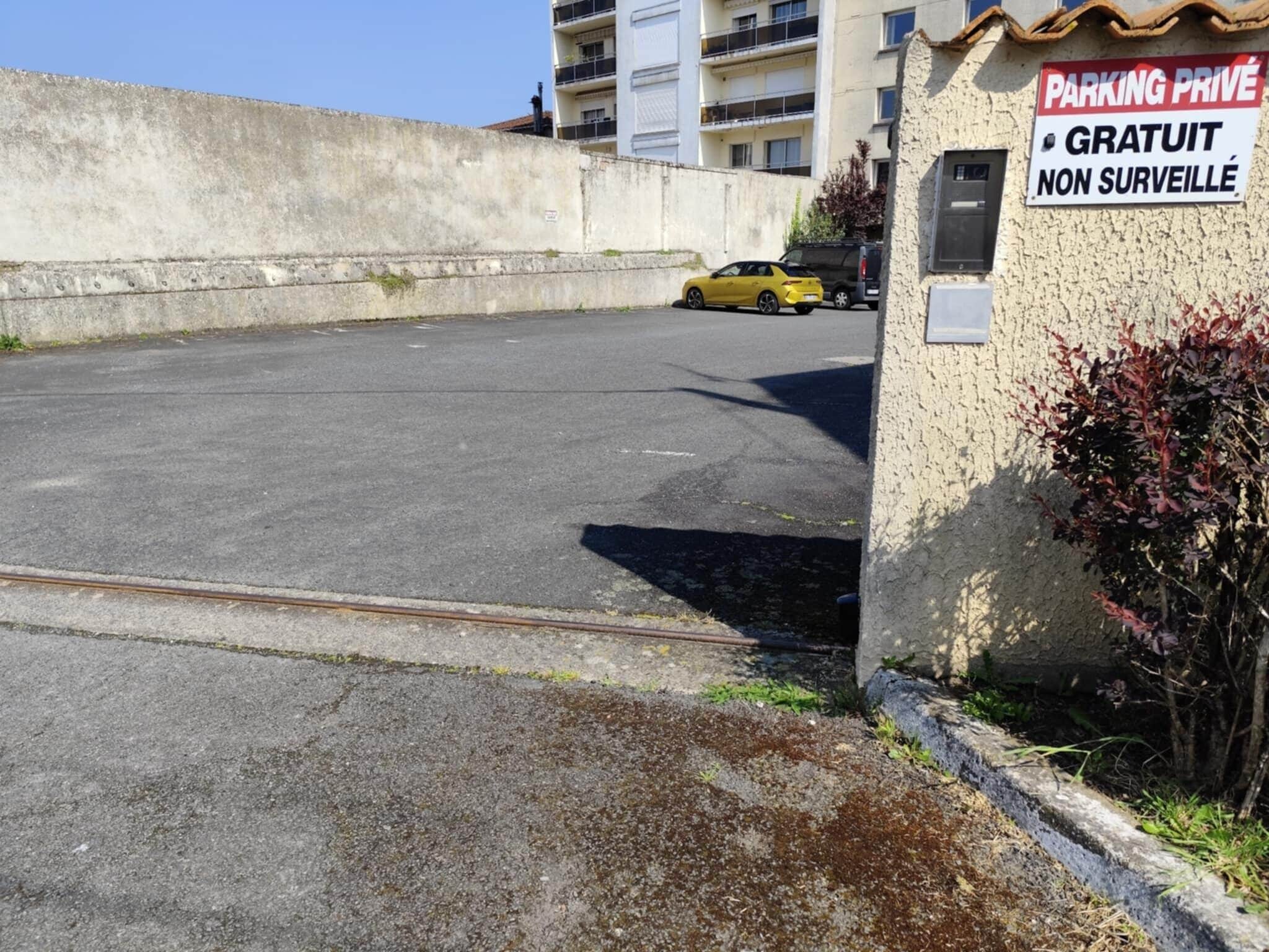 Un espace de stationnement avec un panneau indiquant : « PARCING PRIVÉ GRATUIT, NON SURVEILLÉ ».