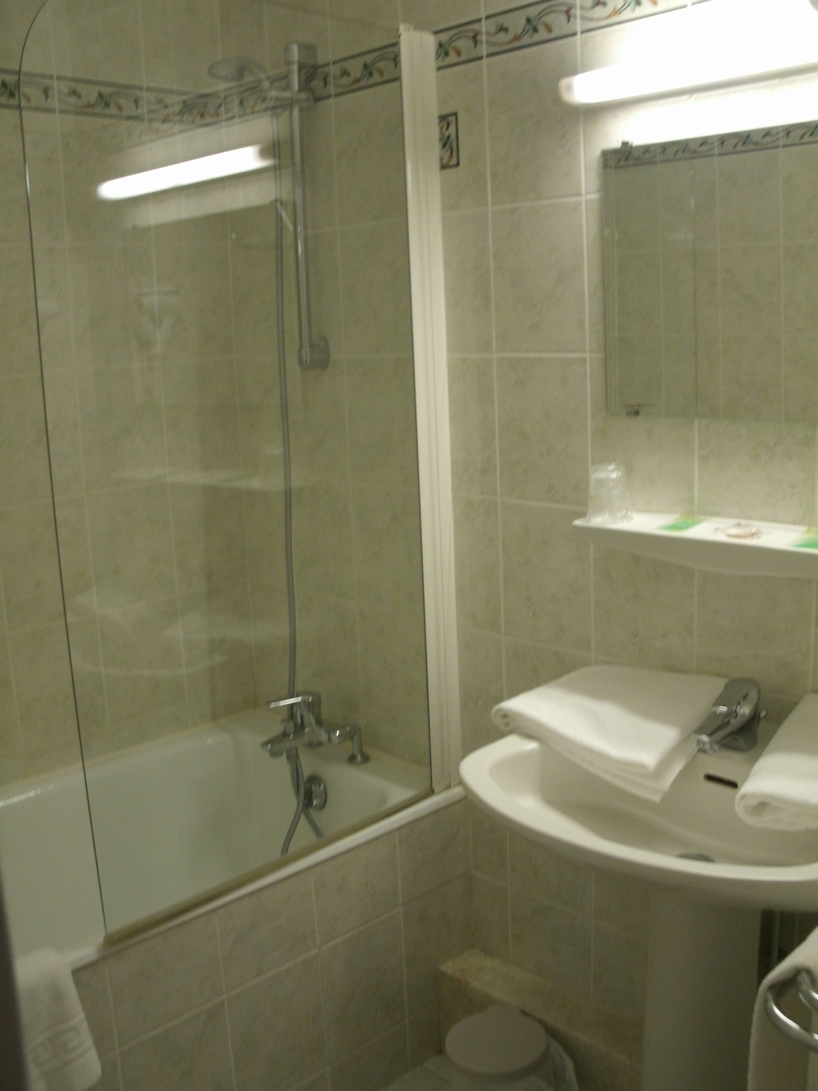 A bathroom with a glass-enclosed shower, a sink, and a mirror above it.
