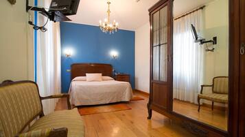 Un dormitorio con cama, una silla, cómoda, espejo y candelabro.