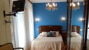 A bedroom with a double bed, a TV mounted on the wall, a chandelier, and a wooden floor. - Casa España (Villaviciosa)