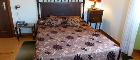 Un dormitorio con cama de madera, colcha estampada, lámparas de noche, una mesita de noche y un teléfono.