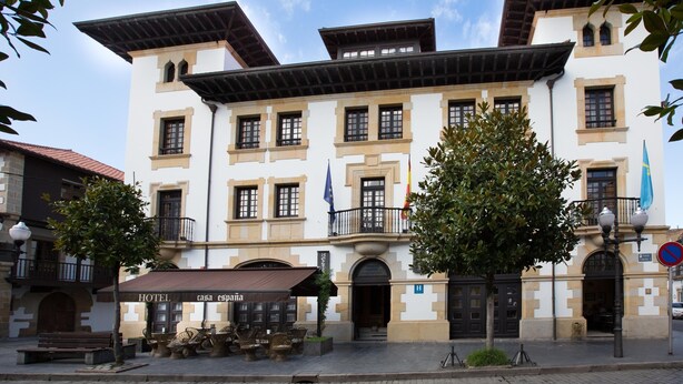 A traditional building with a balcony, a flag, and a sign for a hotel. - Casa España (Villaviciosa)