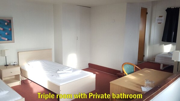 Une chambre triple avec salle de bain privée, comprenant un lit, un bureau, une chaise et une petite table avec des verres.