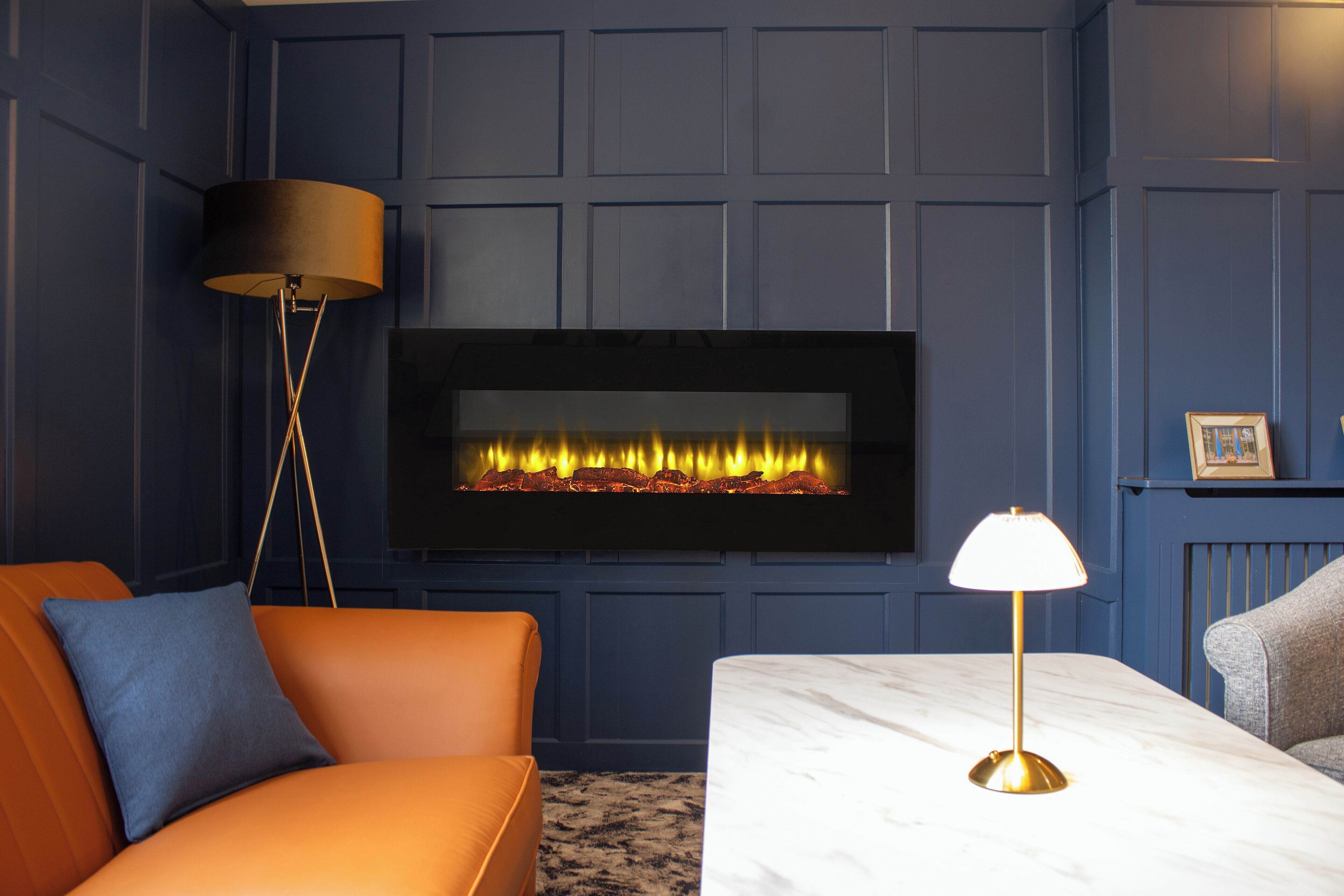 Een kamer met een open haard, een bank, een tafel en een vloerlamp.