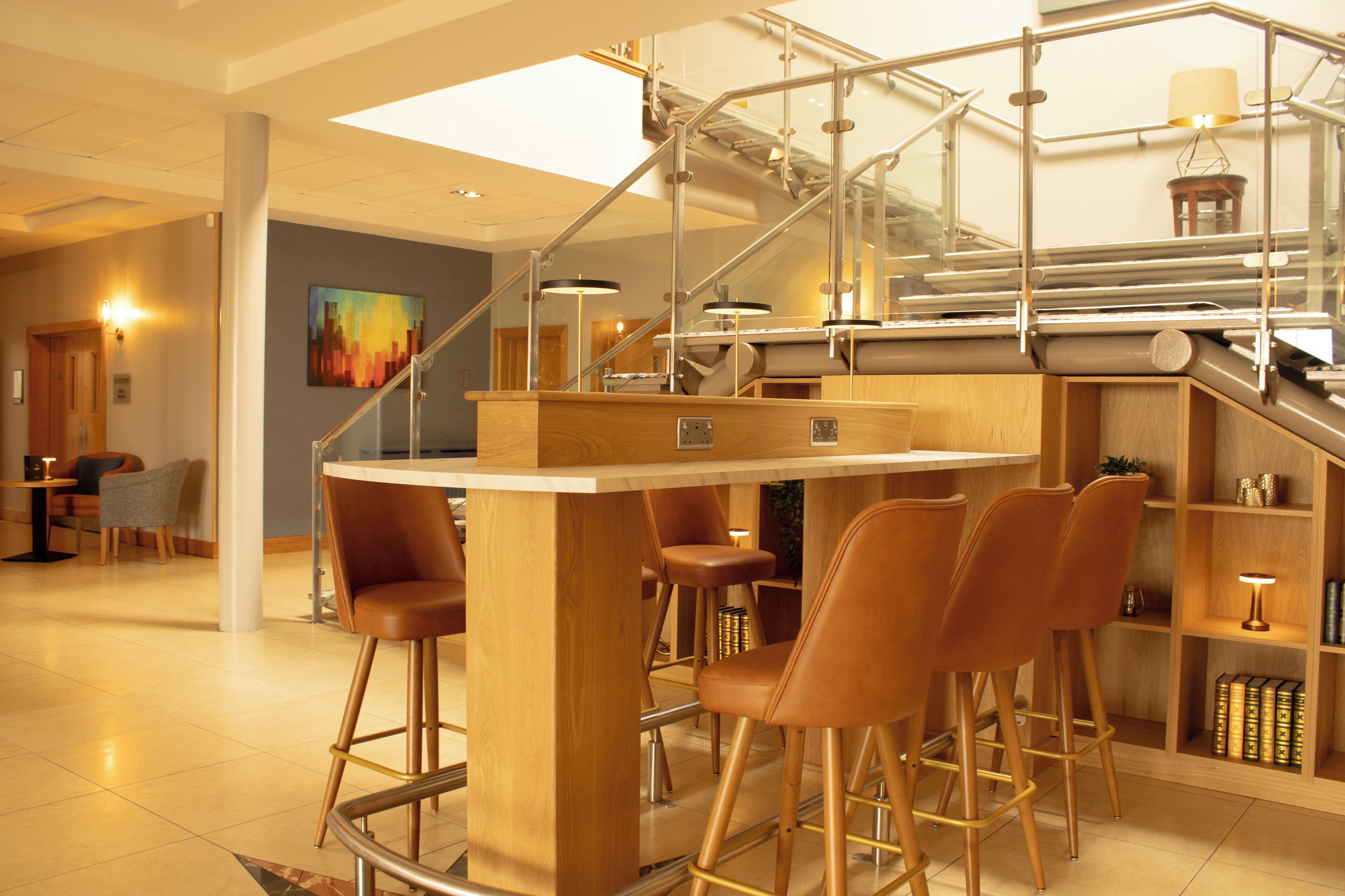 A modern bar area with a wooden bar counter and leather bar stools.