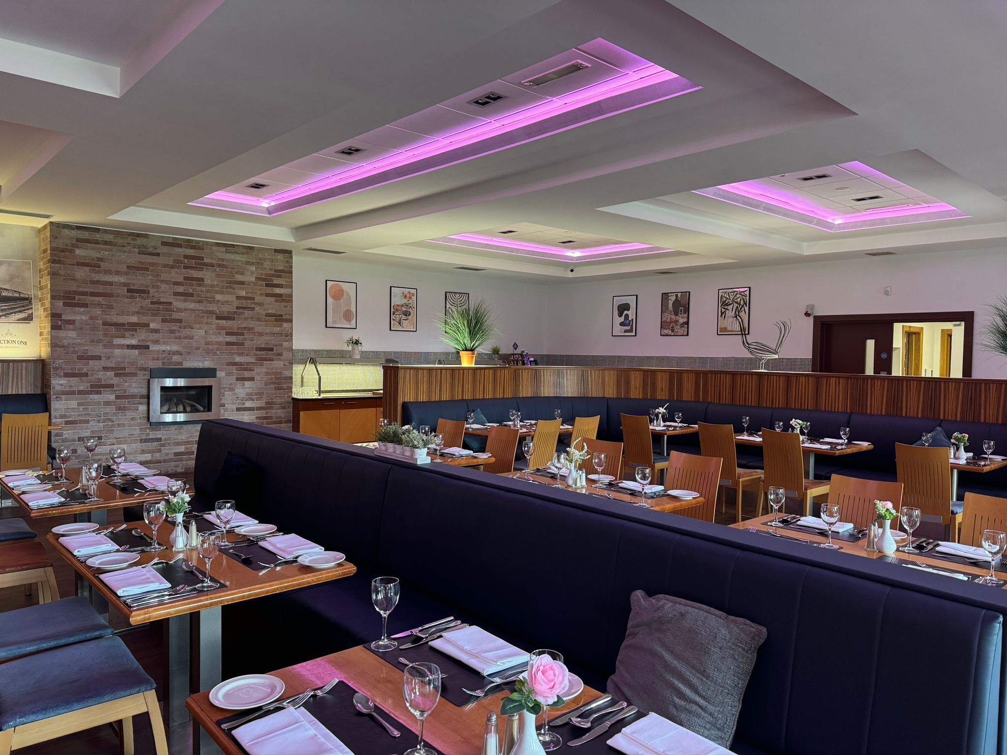 A restaurant with a modern interior, featuring wooden tables and dark seating areas.