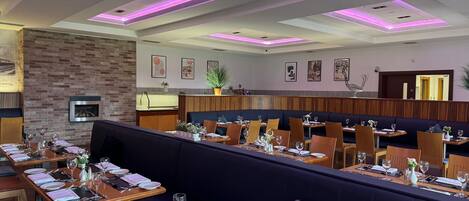 A restaurant with a modern interior, featuring wooden tables and dark seating areas.