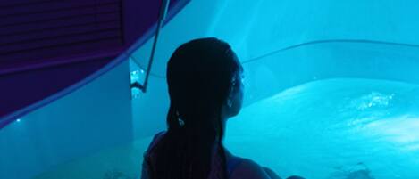 A person sitting in a water-filled, curved structure with a purple and white color scheme.