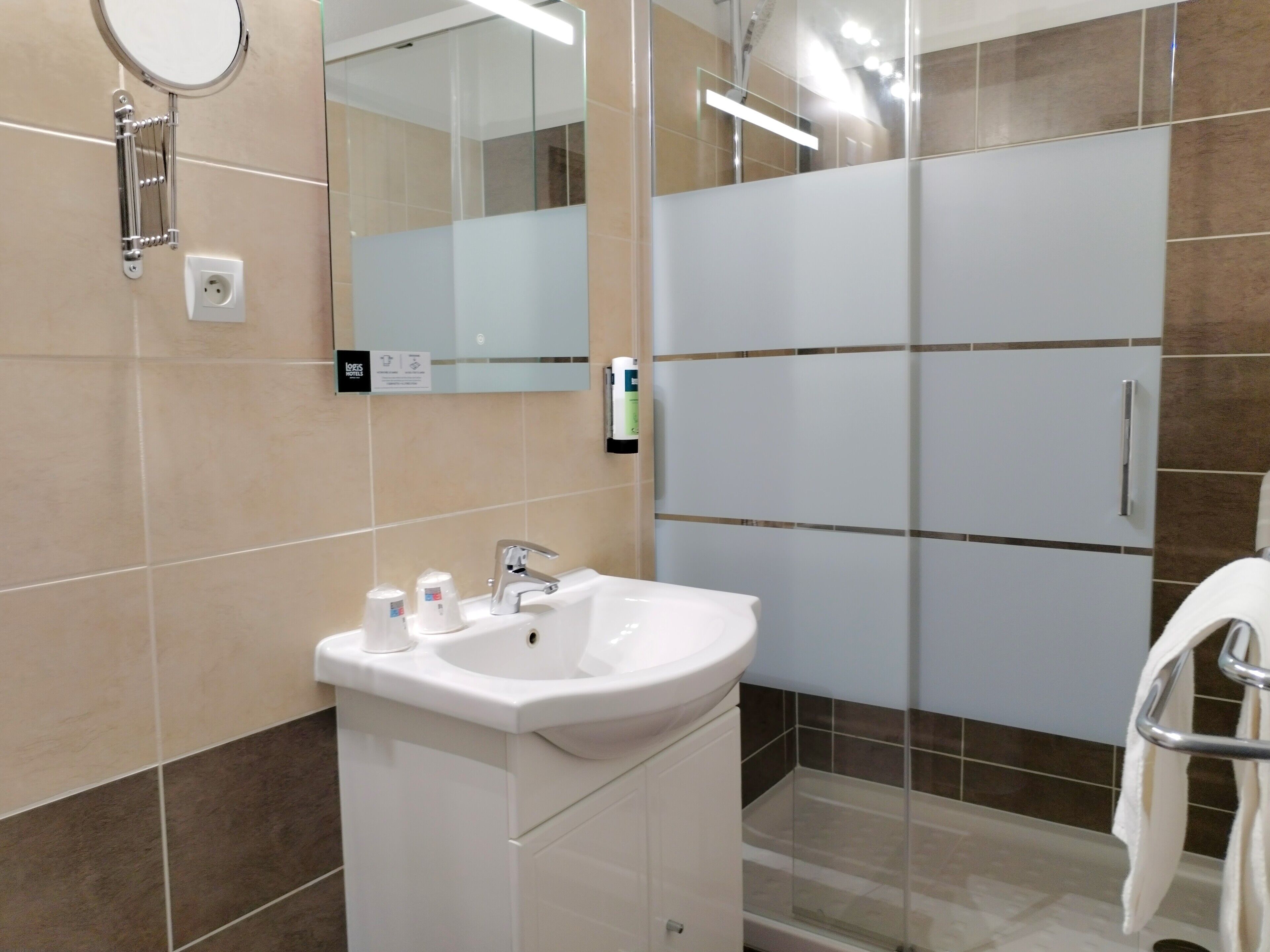 A modern bathroom with a sink, mirror, and glass shower enclosure.