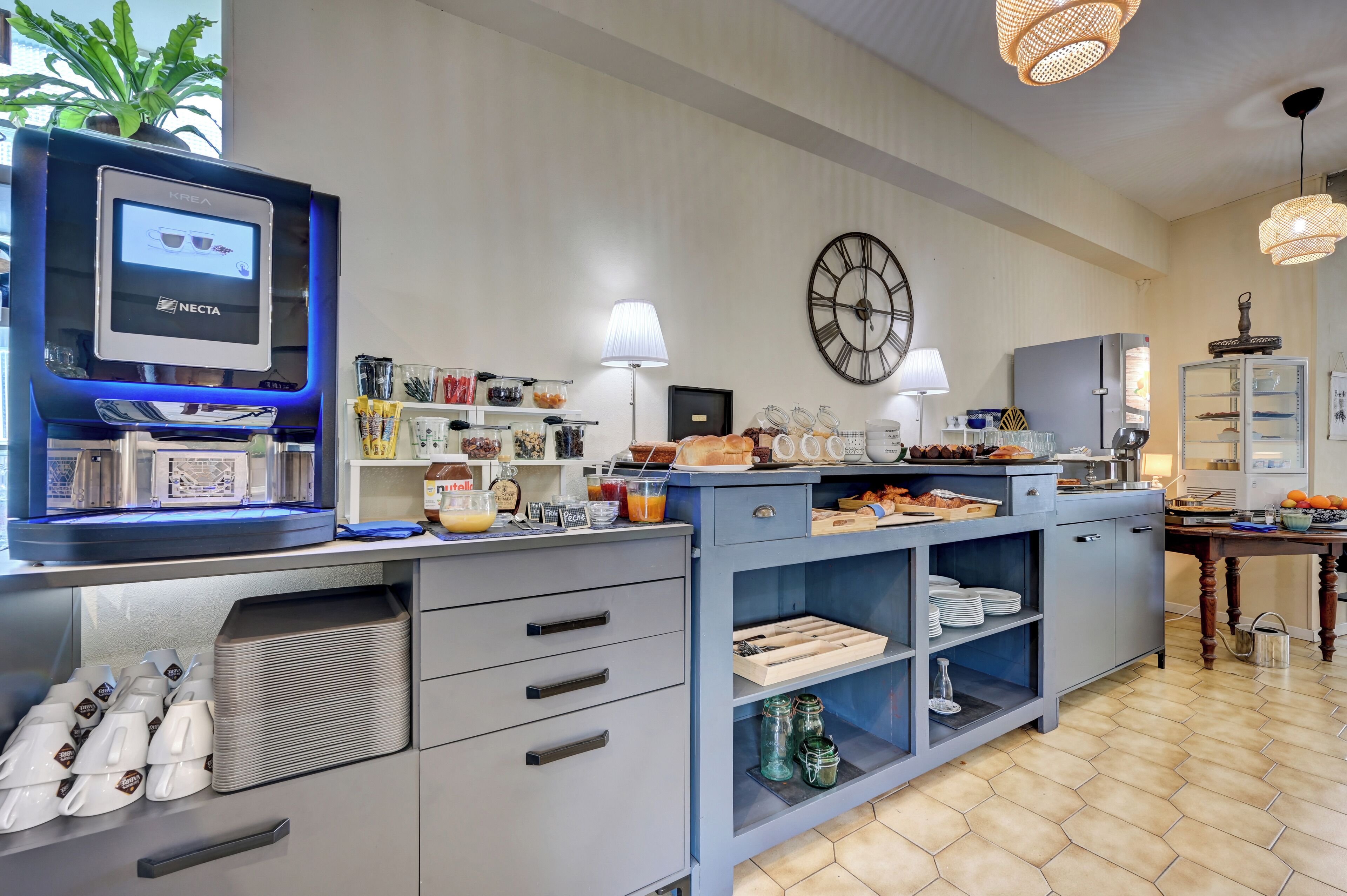 A kitchen area with a coffee machine, a clock, and various food items on shelves.