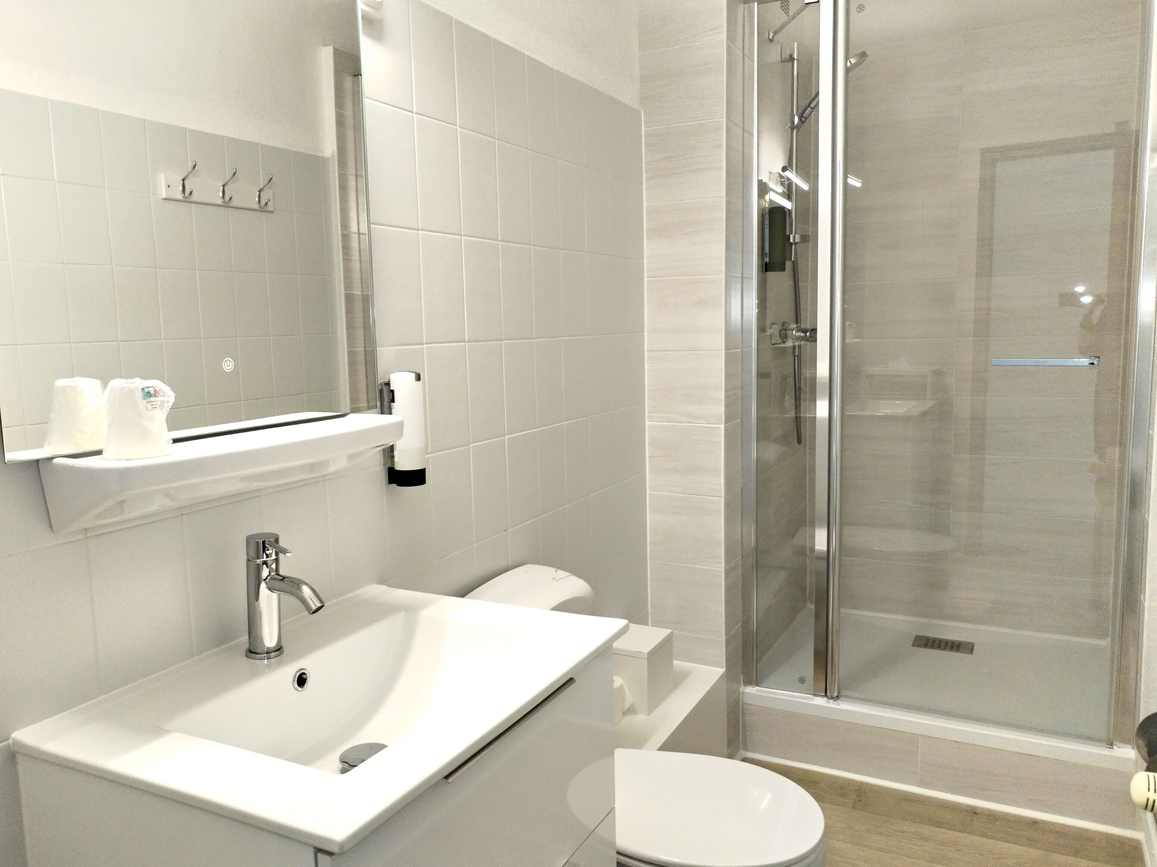 A modern bathroom with a white sink, toilet, and glass-enclosed shower.