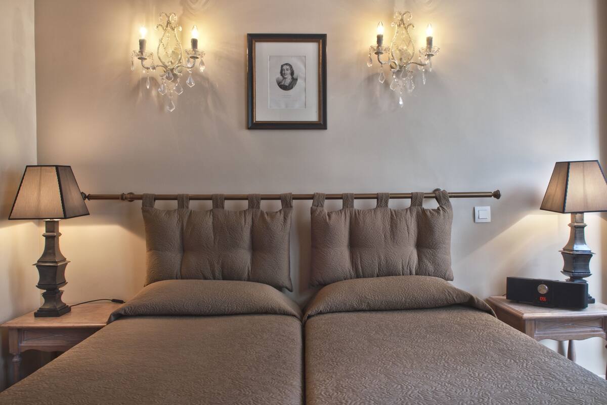 A double bed with a wooden headboard, two bedside tables with lamps, and wall sconces with candles.