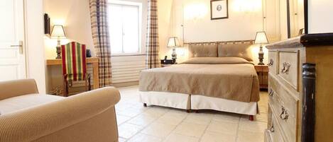 Una habitación de hotel con cama, sofá, cómoda y ventana con cortinas.