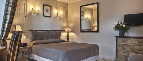 Un dormitorio ordenado con una cama grande, lámparas de noche, un aparador, un televisor y un espejo.
