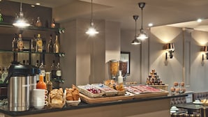 Ein Frühstücksbuffet mit verschiedenen Speisen, Kaffeeautomaten und Getränken.