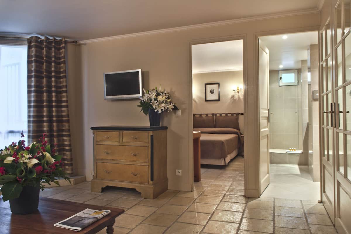 A hotel room with a wooden dresser, a television, a bed, and a bathroom visible through an open door.