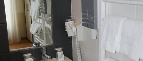A bathroom with a white sink, a mirror, a towel rack, and a toilet.