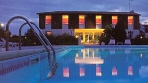 A swimming pool with a building in the background. - Hôtel Le Pont Bernet (Le Pian-Medoc)