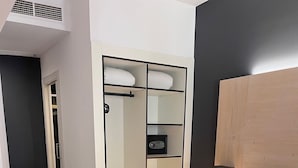 Et hotelværelse med en stor seng, et garderobeskab med flere rum, et natbord med en lampe og trægulv.