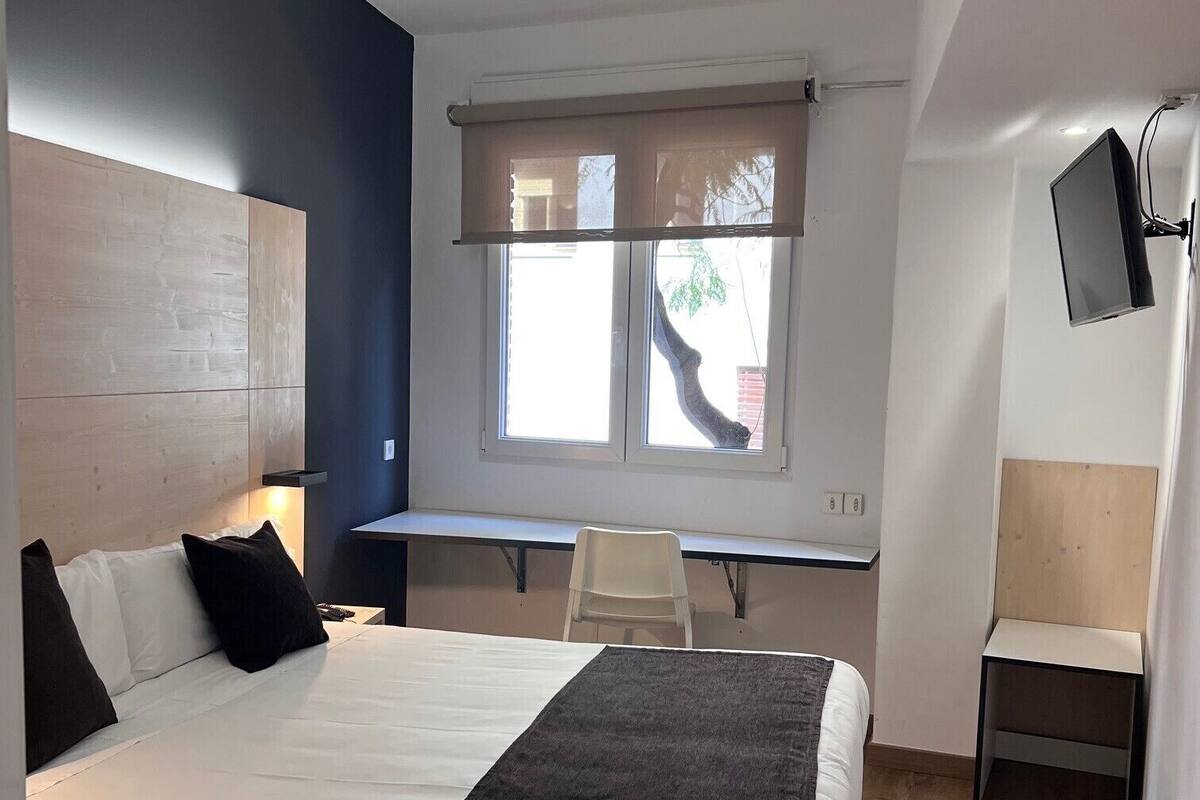 Una habitación de hotel moderna con una cama grande, un escritorio y un televisor.