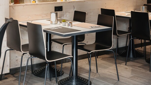 Et moderne spiseområde med et stort vægmaleri af et bybillede og abstrakte figurer.