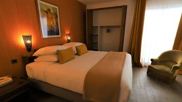 A hotel room with a bed, bedside table, lamp, and a chair.