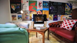 Una habitación acogedora con chimenea, un sofá de cuero, una mesa de madera y varios carteles en la pared.