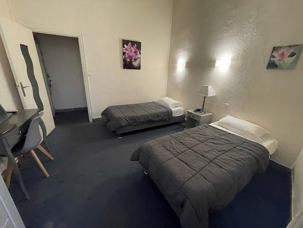 A hotel room with two beds, a desk, and a chair.