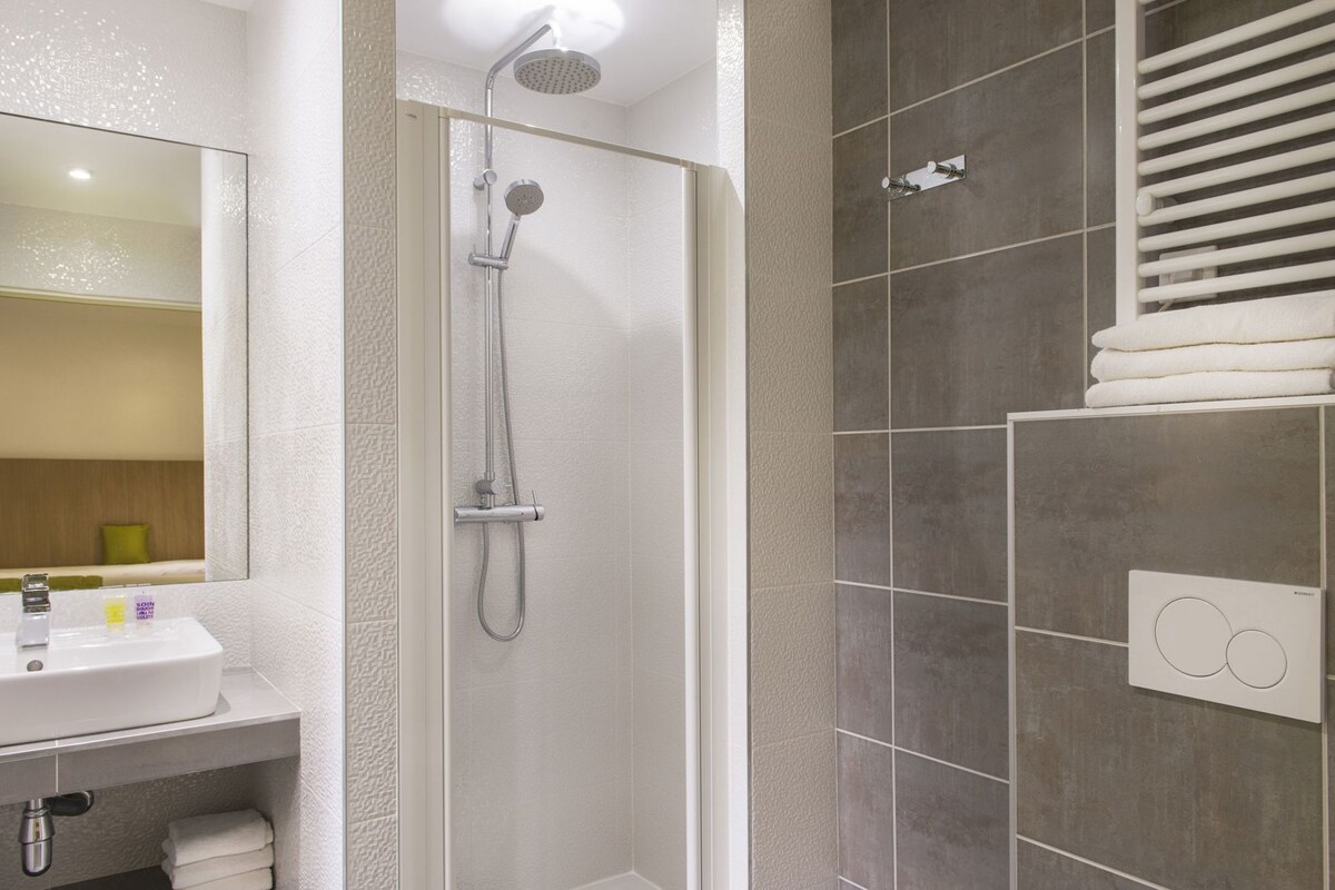 A modern bathroom with a shower, a sink, and a towel rack.
