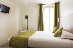 A hotel room with a bed, a television mounted on the wall, a window with curtains, and a mirror. - Hotel Bel Oranger Paris (Paris)