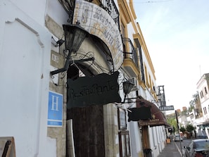 Vista de la calle con un edificio que muestra un letrero que dice 'Restaurante', un letrero azul en forma de 'H' y un letrero 'La Fonda'.