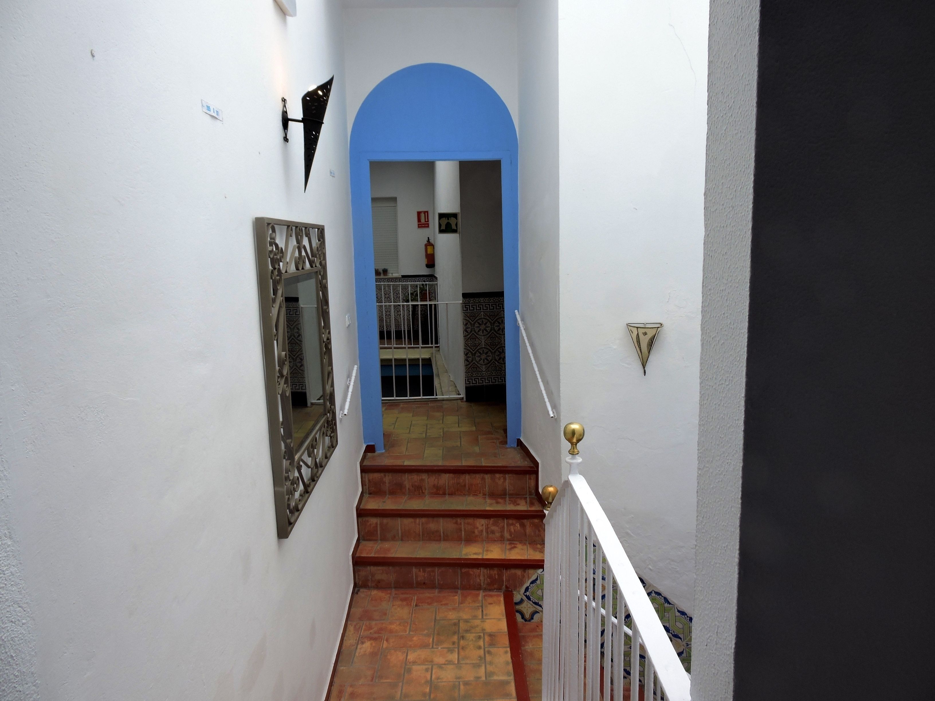 A staircase with a blue archway leading to a room with patterned tiles.