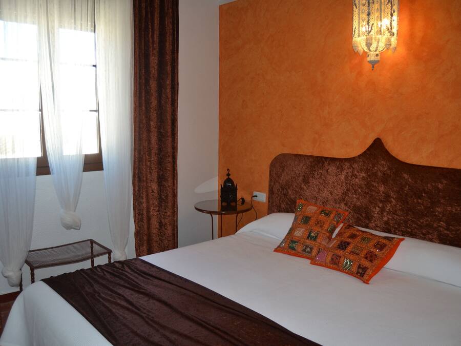 Una habitación de hotel con una cama grande, una mesita de noche, una lámpara y cortinas.