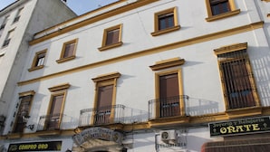 A building with multiple windows, balconies, and signs indicating a hotel and a jewelry store. - Hotel La Fonda del Califa (Arcos de la Frontera)