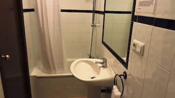 A bathroom with a shower, sink, and a towel rack.