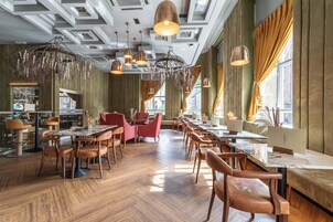 Un restaurante con suelo de madera, varias mesas y sillas, y lámparas colgantes.